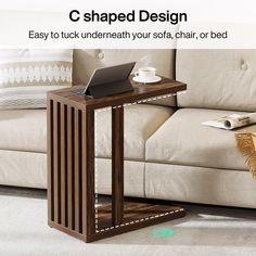 a wooden table with a laptop on it in front of a couch and coffee cup