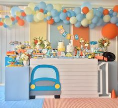 a birthday party with balloons and decorations on the wall, including a car cake table