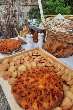 two pizzas sitting on top of wooden trays next to baskets filled with food