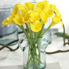 a glass vase filled with yellow flowers on top of a table