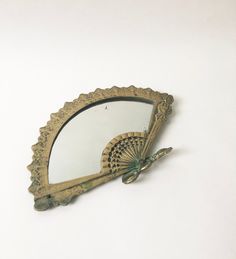 an old mirror with a fan on the top of it's frame, against a white background