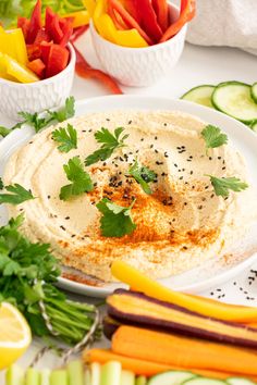 a plate with hummus, carrots, cucumbers and celery