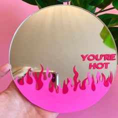 a person holding up a mirror that says you're hot with flames on it