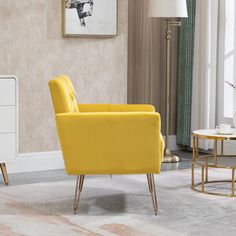 a yellow chair sitting in a living room next to a white table and lamp on top of a rug