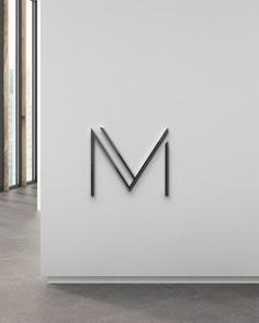 the letter m is displayed in front of a white wall with black metal letters on it