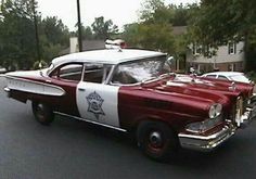 an old red and white police car driving down the street