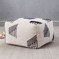 a black and white ottoman sitting on top of a wooden floor next to a potted plant