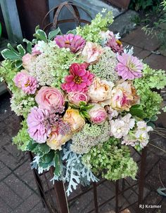 a bouquet of flowers sitting on top of a metal stand next to a brick sidewalk