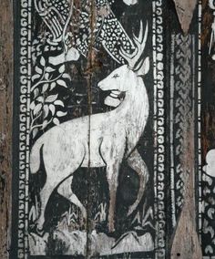 an animal painted on the side of a wooden wall with trees and flowers around it