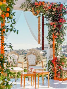 an outdoor wedding setup with flowers and greenery on the wall, chairs and tables