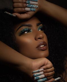 a woman with blue and white nail polish holding her hands on her head while looking at the camera