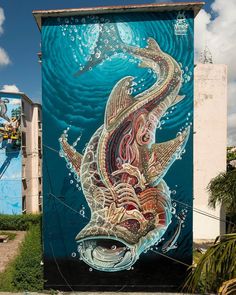 a painting on the side of a building with an image of a fish in it's mouth