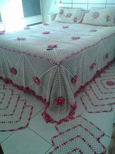 a crocheted bedspread with pink flowers on it in a room next to a window