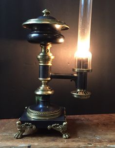 an old fashioned table lamp with a light on it's side and a candle in the middle