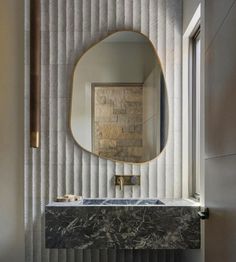 a bathroom with a marble sink and large round mirror on the wall next to it