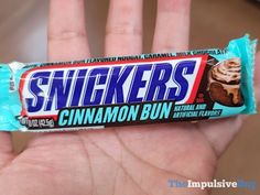 a hand holding a candy bar with the word snickkers on it