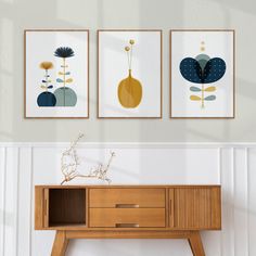 three art prints hanging on the wall above a wooden table