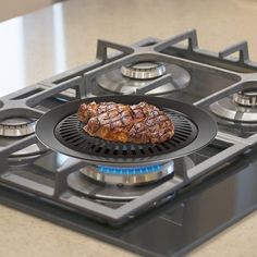 a steak is sitting on top of the burners in this kitchen countertop gas range