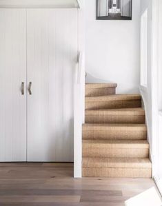 the stairs in this house are made of wood and have been painted white with light brown carpet