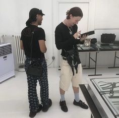 two people standing next to each other in front of a glass table with an object on it