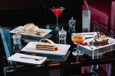 three desserts are sitting on the table in front of glasses and drinks, with one slice missing