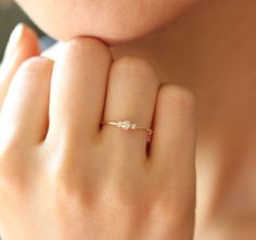 a woman's hand with a diamond ring on her finger, close to her face