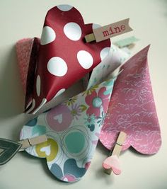 three paper hearts with clothes pins attached to them, one has a name tag on it