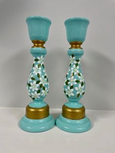 two blue glass candlesticks with flowers painted on them