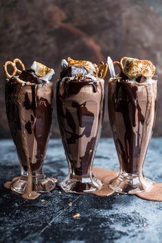 three chocolate milkshakes are sitting on a table