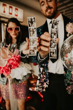 a man and woman are holding up their wedding photos in front of the disco ball