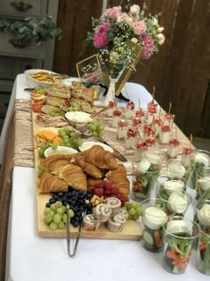 a table topped with lots of food next to cups and vases filled with flowers