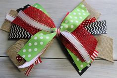 a green and red bow with white polka dots on the top is sitting on a wooden surface