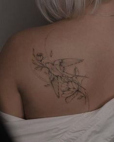 the back of a woman's shoulder with a flower tattoo on her left side