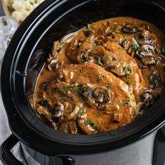 a crock pot filled with meat and mushrooms