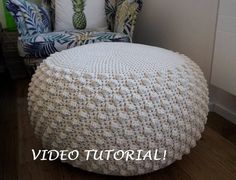 a white crocheted ottoman sitting on top of a wooden floor next to a chair