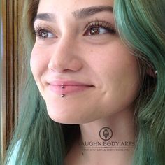 a woman with green hair and piercings on her nose looking at the camera smiling