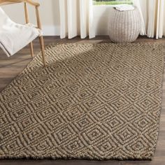 a large rug in the corner of a room with a chair and window behind it