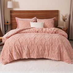 a bed with a pink comforter and pillows