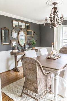 a dining room table with white chairs and a chandelier hanging from the ceiling