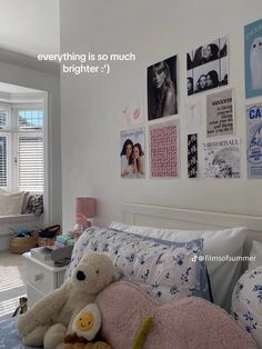 there is a teddy bear that is laying on the bed in front of some pictures