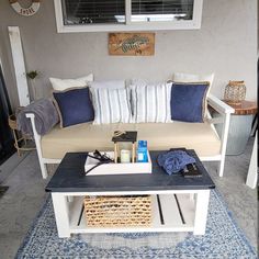 a couch sitting on top of a blue rug in front of a white coffee table