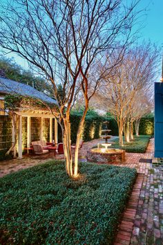 The stunning terrace and garden at Greatmen Cottage Vacation Rental Home in New Orleans, Louisiana, USA.  We see crape myrtles, asian jasmine, a pergola with a vintage Howell Chair seating area, a four-tiered cast iron fountain cascading water down into a brick octagonal pool.  It is evening and key plants a structures are featured with garden lights. Creole Cottage, New Orleans Vacation, Louisiana Travel, Louisiana Usa, Visit New Orleans, New Orleans French Quarter, New Orleans Travel, Walking Routes, Vacation Home Rentals