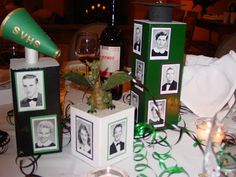 the table is set with wine glasses, candles and pictures on cubes that are decorated with green ribbon