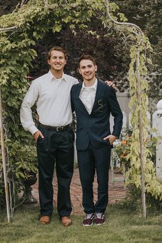 two men standing next to each other under an arbor