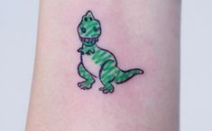 a small dinosaur tattoo on the arm