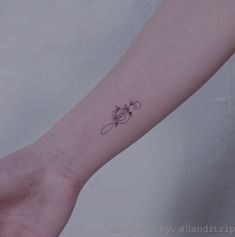 a woman's arm with a small flower tattoo on the left side of her arm