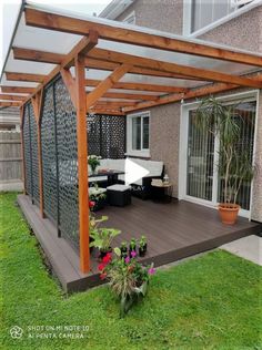 an outdoor patio with wooden pergols and plants on the grass in front of it