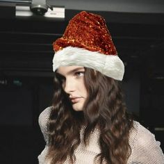 a woman with long hair wearing a red and white santa hat on top of her head