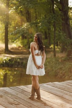 a woman in a white dress standing on a dock