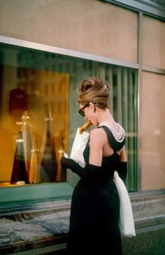 a woman walking down the street in front of a store window looking at her cell phone